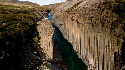 Breathtaking views of Studlagil Canyon showcase towering basalt columns framing a turquoise river....