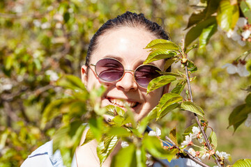 Young asian tourist woman traveling in beautiful spring park full of cherry blossom flower or Sakura on a sunny day. Girl enjoying with smiling face.