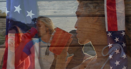 Drinking friends holding red plastic cups at lakeshore during sunset, American flag overlay
