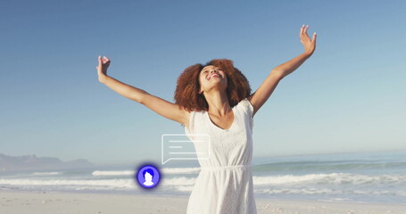 Spreading arms woman wearing white sleeveless dress at sandy shore, with ocean waves and mountains