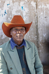 Africa village, single elderly african man waiting in a bus station, wearing a cowboy hat