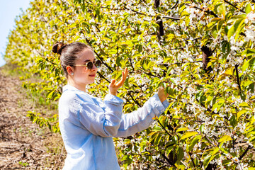 A very beautiful portrait of a special and beautiful lady as she admires the cherry orchard and tries to smell this pleasant scent. It is a bright and warm time. Nature delights us with this scene.