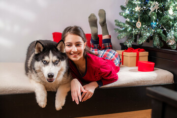 smiling girl and husky dog lie on bed. Christmas holiday celebration