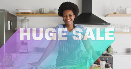 Smiling woman wearing striped apron leaning on kitchen island, with fresh produce and blender