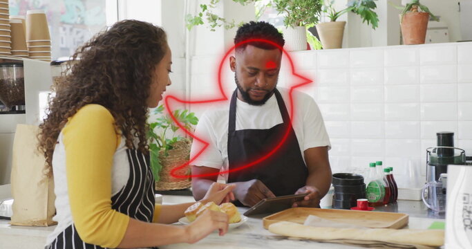 Holding tablet, African American barista using app behind marble counter, with croissant and plants - Powered by Adobe
