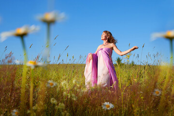 Woman in pink dress enjoying nature in a vibrant flower field under a clear blue sky