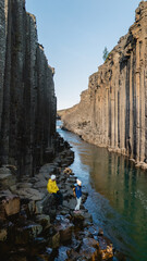 Two individuals discover the stunning landscape of Studlagil Canyon in Iceland, surrounded by...