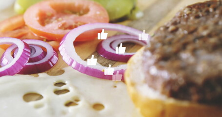 Showing board with melted cheese onion rings in kitchen, tomato pickle patty bun, thumbs-up icons