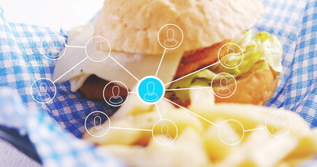 Showing burger sandwich resting on checkered liner in cafe, with cheese, fries and network graphic