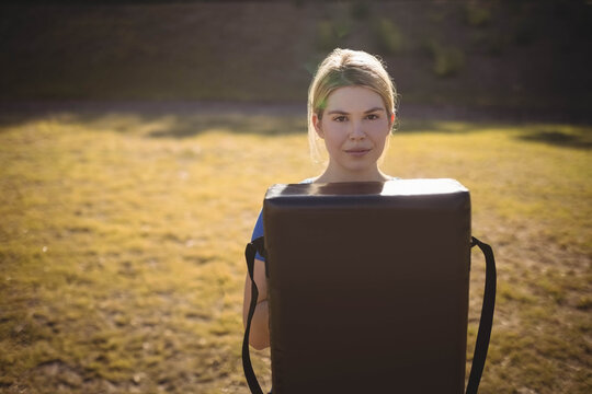Fototapeta Training pad being held at chest in sunlit golden field near shaded shrubs during late afternoon