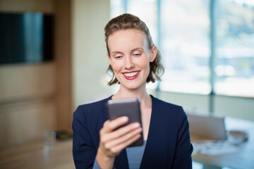 Obraz premium Smartphone sitting on wooden table in meeting room, with wall-mounted screen and scattered papers
