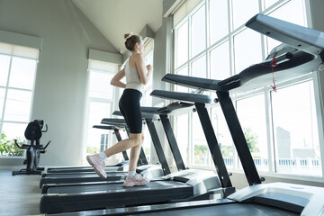 Woman, Running and exercising. Woman running on treadmill in gym. Young woman wearing sportswear...