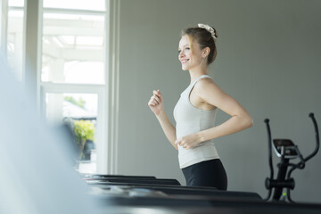 Woman, Running and exercising. Woman running on treadmill in gym. Young woman wearing sportswear...