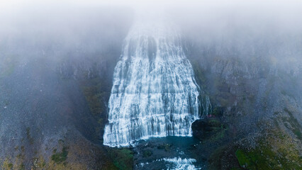 Cascading down rugged cliffs, a majestic waterfall of Iceland flows with vibrant energy. Surrounded by mist, it creates a captivating atmosphere. Dynjandi waterfall, Westfjord, Iceland