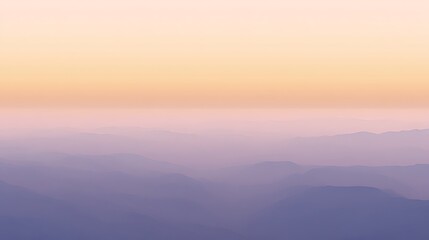 Obraz premium Aerial view of misty mountain range landscape with soft pastel sunrise colors