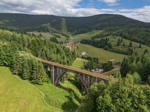 Aerial view of the Telg&Atilde;&iexcl;rt Viaduct cutting through the vibrant green landscape, a stark contrast against the dense forest, Telg&Atilde;&iexcl;rt, Brezno District, Slovakia.
