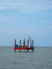 Offshore construction platform by wind turbines on a calm sea. Abergele, Traeth Pensarn, North Wales.