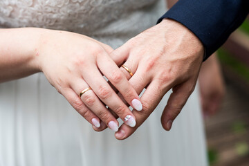 Manos de una novia y un novio recién casados enseñando las alianzas y posadas en sus manos