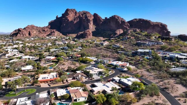 Aerial view of Camelback Mountain and Echo Canyon Trail, a rugged landscape contrasting with the scattered houses below, basking under a bright blue sky, Phoenix, Arizona, United States.