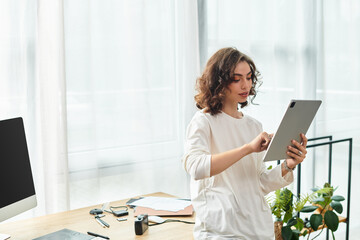 Young woman with curly hair enjoys freelancing from her home workspace in daylight