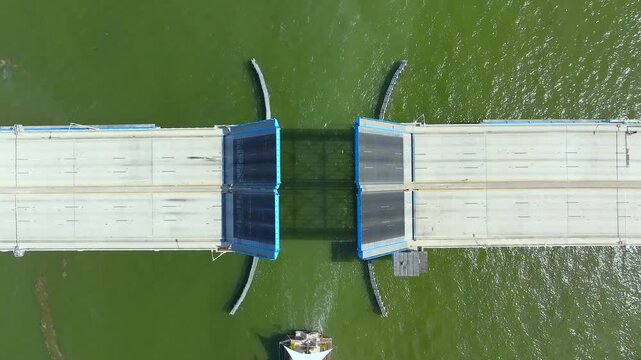 Aerial view of the open 79th Street Causeway bridge over green water, revealing concrete textures and a passing jet ski, North Bay Village, Florida, United States.
