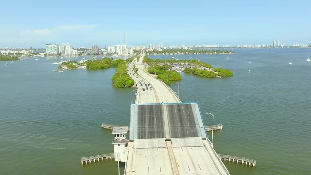 Aerial view of the 79th Street Causeway bridge, with its blue accents contrasting against the green waters, North Bay Village, Florida, United States.