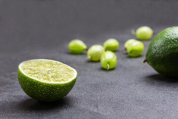 Lime halves and gooseberry berries on black background. Close up.