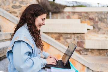 Young woman using laptop computer while sitting on steps outdoors