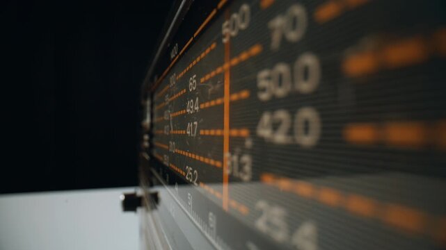 Retro radio searching waves broadcasting music in dark apartment closeup.