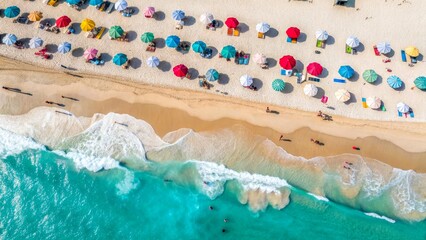 Aerial view of the beach with colorful umbrellas and turquoise waves. People enjoying a summer vacation on the warm sand. Ideal for tourism and resort life themes.