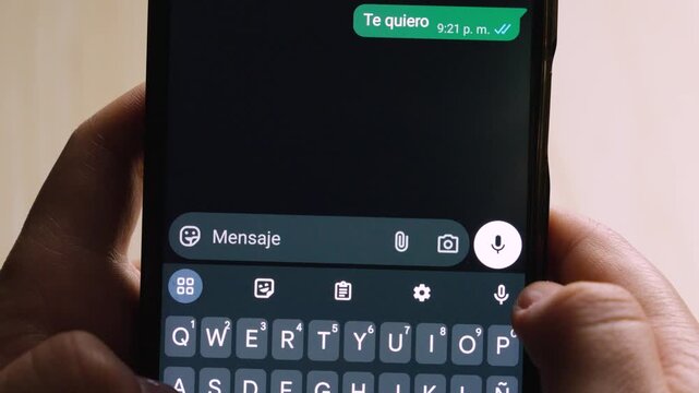 Close-up of a person holding a smartphone while typing the affectionate Spanish phrase "Te quiero" in a chat.