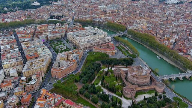 Cinematic drone footage sweeping over Rome&rsquo;s Castel Sant&rsquo;Angelo and Ponte Sant&rsquo;Angelo on the Tiber River, with the Palace of Justice, tree‑lined embankments and terracotta rooftops beyond in Italy.