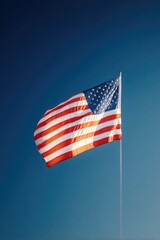 Obraz premium solitary american flag waving against deep blue sky with ample copy space embodying patriot day solemnity