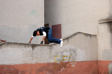 A guy does an acrobatic trick at the stadium by jumping over a small fence	
