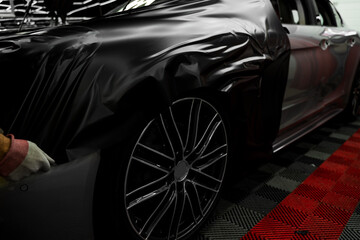 Car wrapping process using black matte vinyl stretched into place. Careful application and...