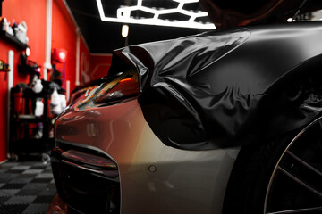 Matte black vinyl wrapping around car with smooth alignment over curves and edges. Matte black...