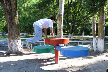 A guy does a parkour-style trick by jumping between his hands over a large metal stand	
