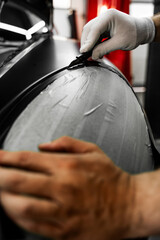 Vinyl film is carefully applied and trimmed with a blade for flawless vehicle wrapping results....