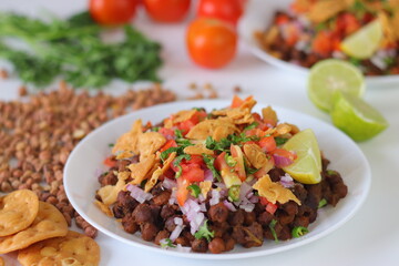 Chana Chaat with crushed papdi, topped with chickpeas, onions, tomatoes, chilies, coriander, and lime