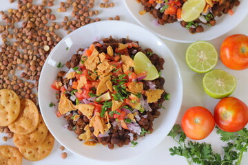 Chana Chaat with crushed papdi, topped with chickpeas, onions, tomatoes, chilies, coriander, and lime