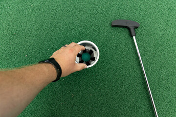 hole in one picking up a golf ball from a hole