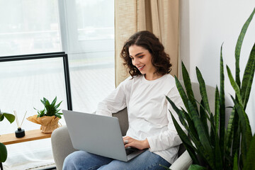 Freelancer immersed in work from home with natural light and greenery surrounding her