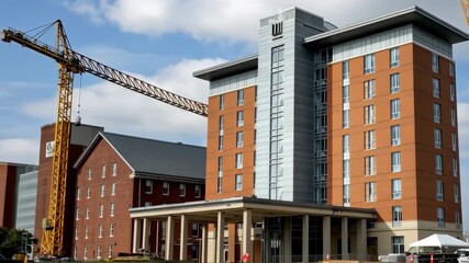 Construction of new modern hotel in urban area with crane and workers on site during daytime