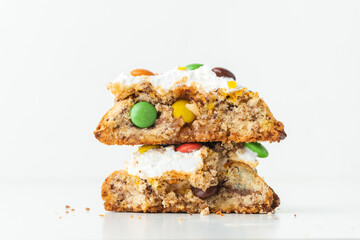Fresh chocolate American chip cookie broken in half and decorated with multicolored candies on white background. Close up of cookies with chocolate colored candies inside