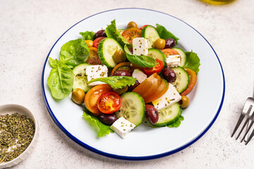 Greek salad of fresh cucumber, tomato, sweet pepper, lettuce, feta cheese and olives with olive oil on a white background. Healthy food. High quality photo