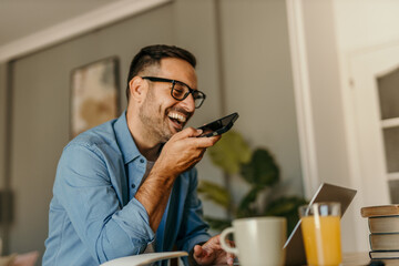 Entrepreneur recording voice message on smartphone while working from home office