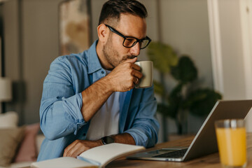 Focused freelancer enjoying coffee while working from home office