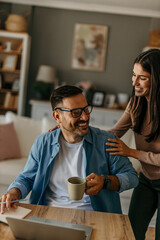 Happy couple working from home, woman supporting her husband