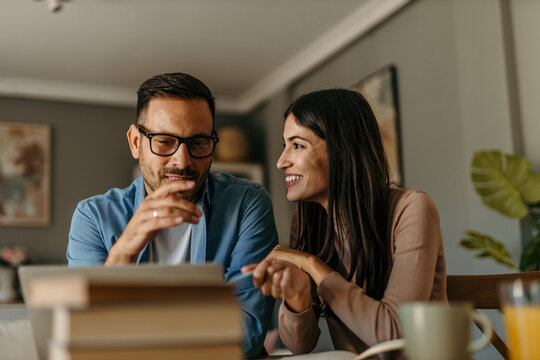 Couple enjoying working from home using tablet and books - Powered by Adobe