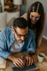 Couple working from home having fun using laptop computer